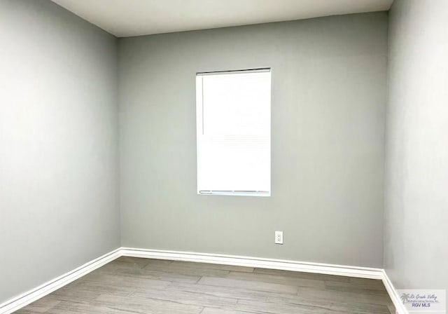 spare room featuring wood finished floors and baseboards