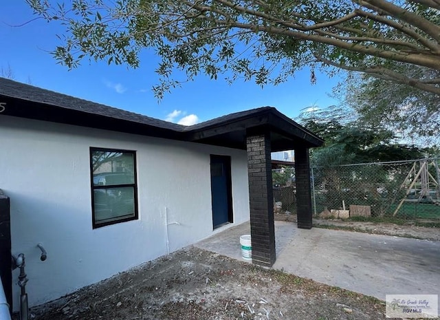 doorway to property with a patio area, stucco siding, and fence