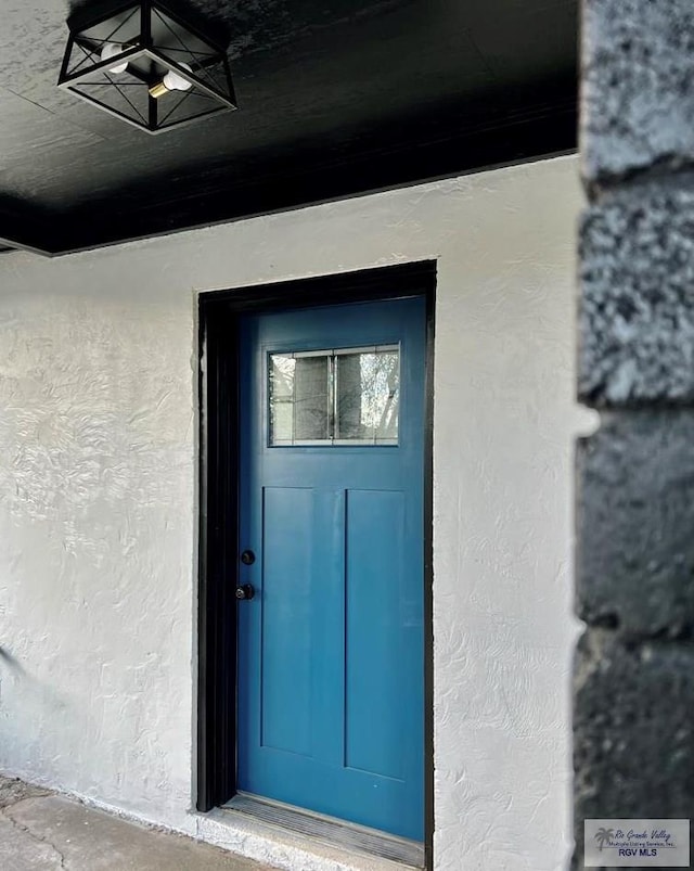 view of exterior entry featuring stucco siding and a ceiling fan