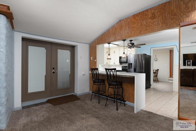 kitchen with a kitchen bar, kitchen peninsula, stainless steel appliances, pendant lighting, and lofted ceiling