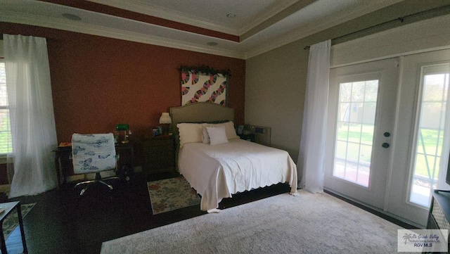 bedroom with multiple windows, a tray ceiling, carpet floors, and ornamental molding