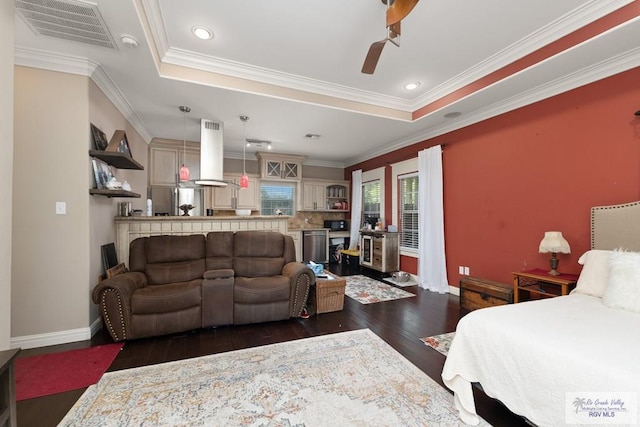 bedroom featuring a raised ceiling, ornamental molding, dark hardwood / wood-style floors, and stainless steel refrigerator with ice dispenser