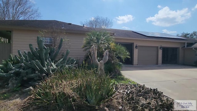 ranch-style home with a garage and solar panels