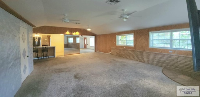 unfurnished living room featuring lofted ceiling, ceiling fan, and carpet