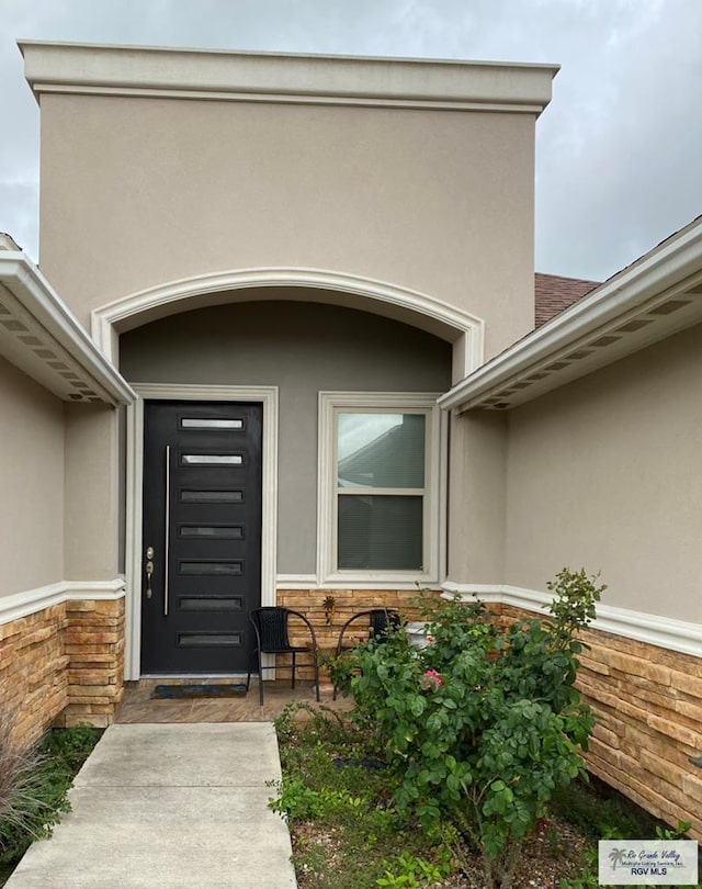 property entrance with stone siding and stucco siding