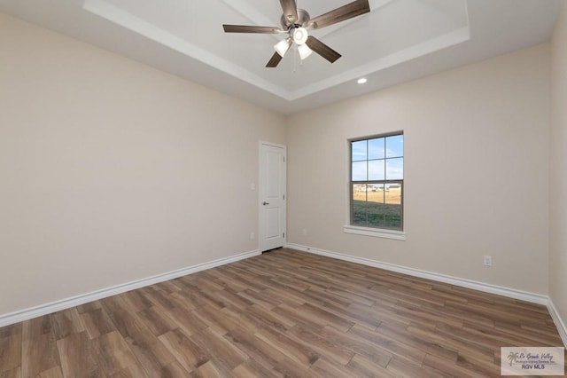 empty room featuring ceiling fan, a raised ceiling, and hardwood / wood-style floors