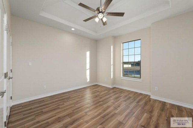 unfurnished room featuring ceiling fan, dark hardwood / wood-style floors, and a raised ceiling