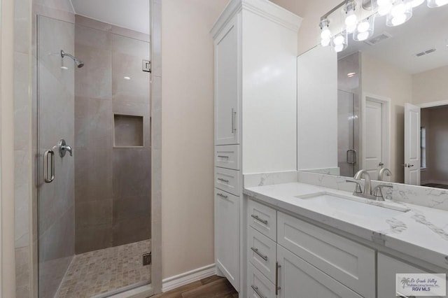 bathroom featuring hardwood / wood-style flooring, vanity, and a shower with shower door