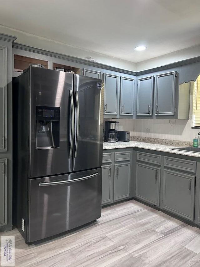 kitchen with light hardwood / wood-style flooring, sink, gray cabinetry, and stainless steel fridge with ice dispenser