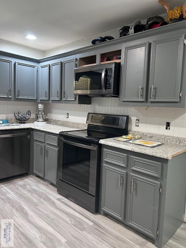 kitchen with electric stove, light hardwood / wood-style flooring, black dishwasher, gray cabinets, and decorative backsplash