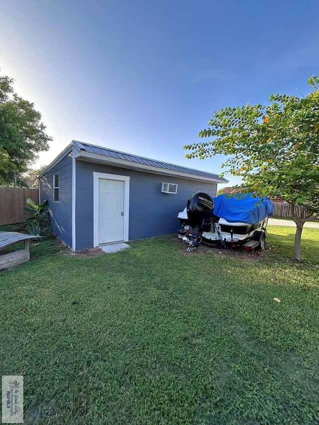 view of outbuilding featuring a wall unit AC and a lawn