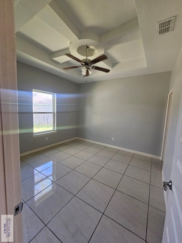 tiled spare room with ceiling fan and a raised ceiling