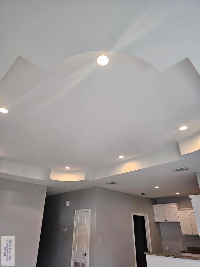 room details featuring white cabinets and dark stone counters