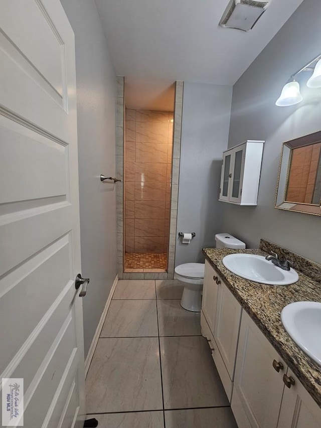 bathroom with a tile shower, vanity, and toilet