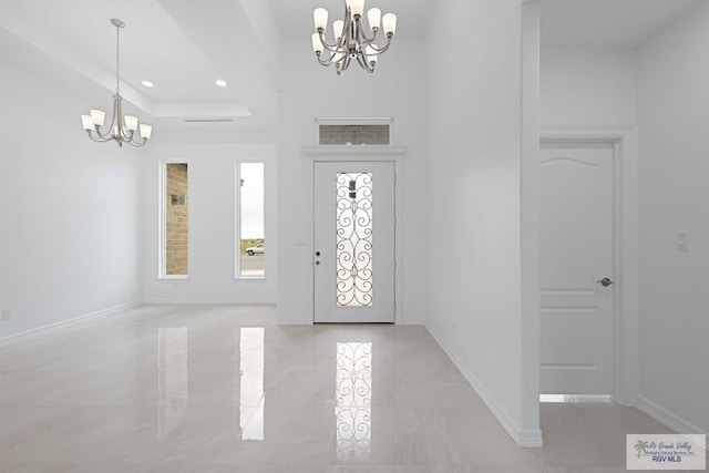 foyer entrance featuring a raised ceiling and an inviting chandelier