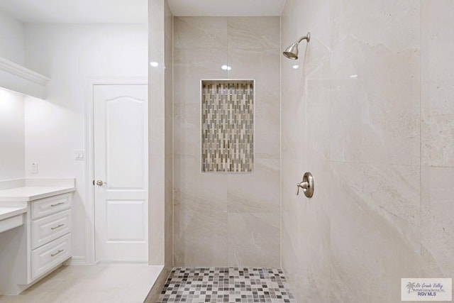 bathroom with tile patterned floors, vanity, and tiled shower