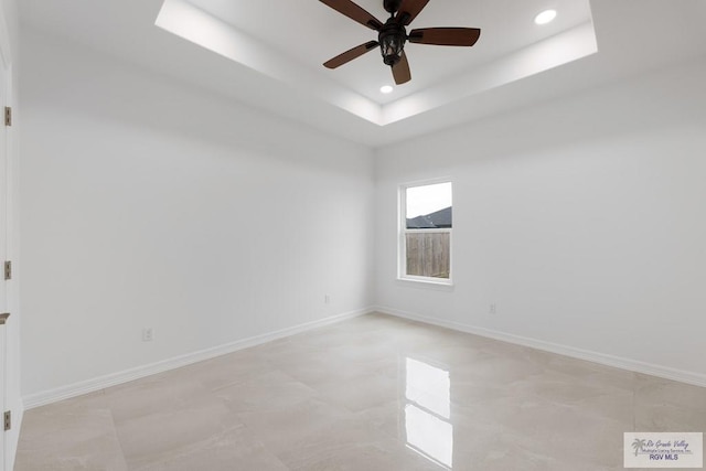 empty room featuring ceiling fan and a raised ceiling