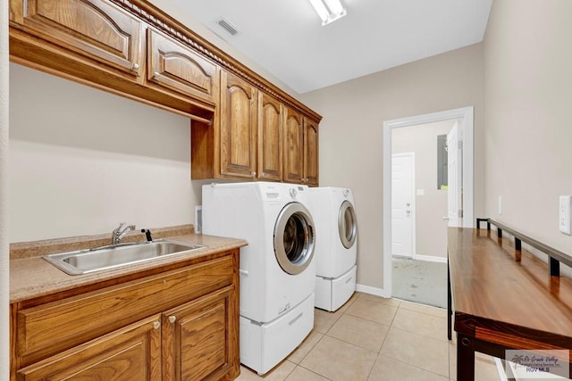 washroom featuring washing machine and clothes dryer, light tile patterned floors, cabinet space, visible vents, and a sink