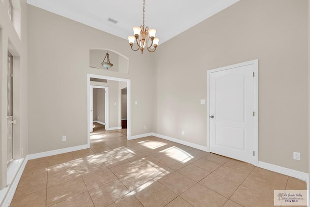 spare room with light tile patterned floors, visible vents, an inviting chandelier, high vaulted ceiling, and baseboards