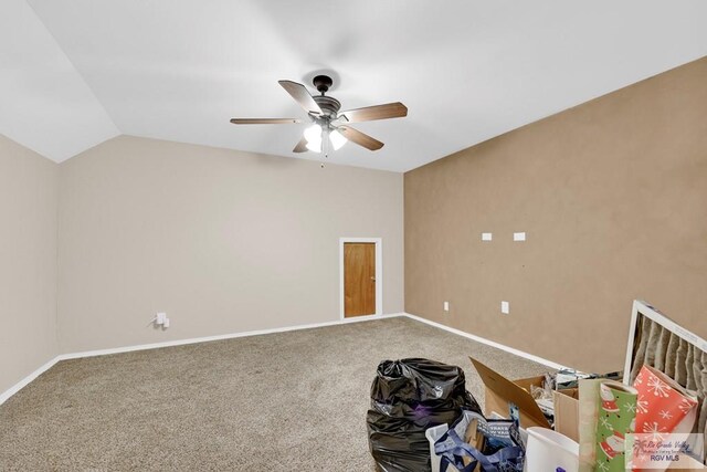 carpeted empty room with baseboards, vaulted ceiling, and a ceiling fan