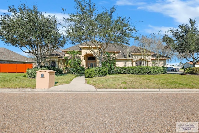 mediterranean / spanish house with a front yard, fence, and stucco siding