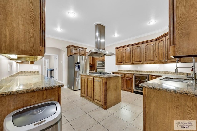 kitchen with wine cooler, a kitchen island, appliances with stainless steel finishes, brown cabinetry, and island exhaust hood