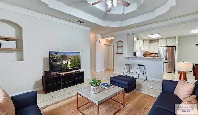 living room featuring a raised ceiling, light tile patterned flooring, crown molding, and visible vents