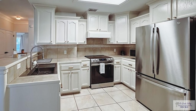 kitchen with under cabinet range hood, stainless steel appliances, a sink, white cabinetry, and light countertops