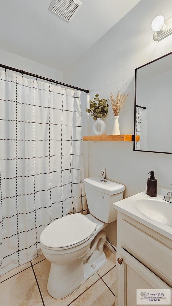 full bathroom featuring visible vents, toilet, a shower with curtain, tile patterned flooring, and vanity