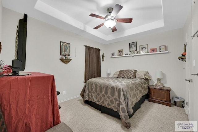 carpeted bedroom featuring baseboards, a ceiling fan, and a tray ceiling