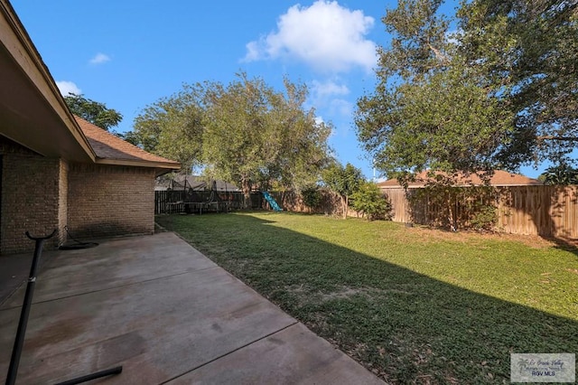 view of yard featuring a patio, a fenced backyard, and a playground