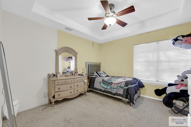 bedroom featuring ceiling fan, light carpet, a raised ceiling, baseboards, and visible vents