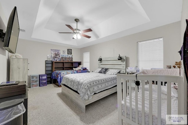 bedroom featuring a tray ceiling, carpet flooring, and ceiling fan
