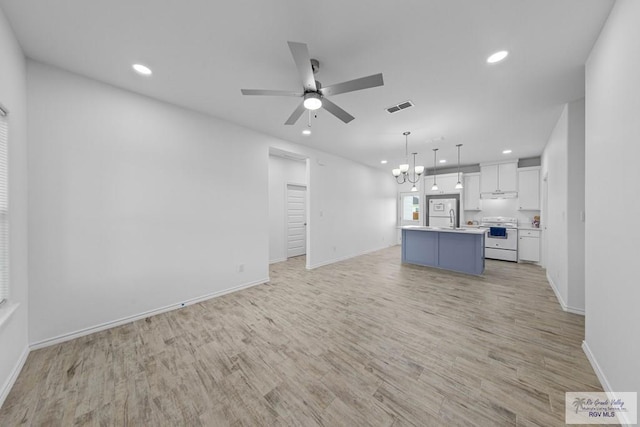 unfurnished living room with ceiling fan with notable chandelier, light wood-type flooring, and sink