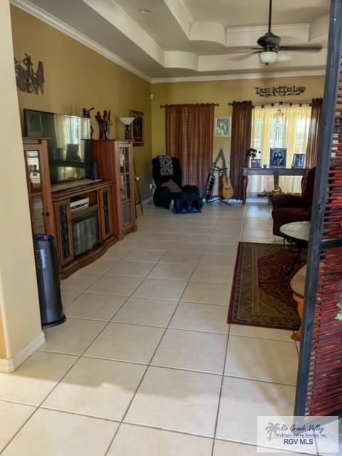 5303 Rustic Manor Dr, Brownsville, TX 78526 - living room with crown molding, baseboards, a raised ceiling, a ceiling fan, and light tile patterned floors