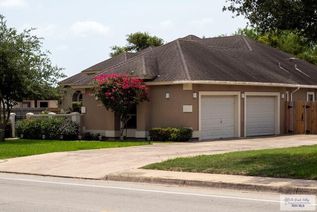 5303 Rustic Manor Dr, Brownsville, TX 78526 - view of front of property with an attached garage, fence, driveway, and stucco siding