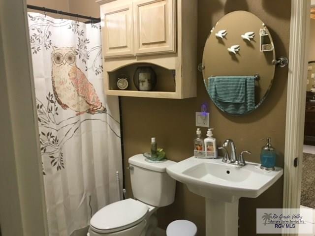 5303 Rustic Manor Dr, Brownsville, TX 78526 - bathroom with a sink, curtained shower, and toilet