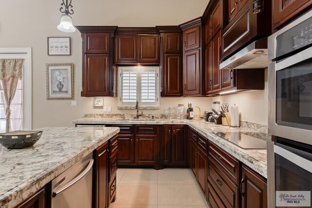 kitchen featuring decorative light fixtures, stainless steel appliances, a sink, light tile patterned flooring, and light stone countertops