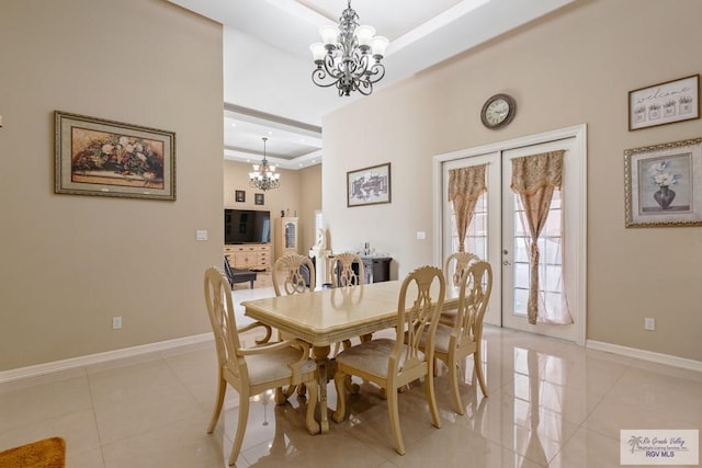 dining room with a tray ceiling, a notable chandelier, french doors, light tile patterned floors, and baseboards