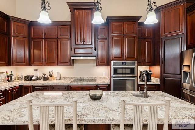 kitchen featuring hanging light fixtures, a sink, light stone counters, and appliances with stainless steel finishes