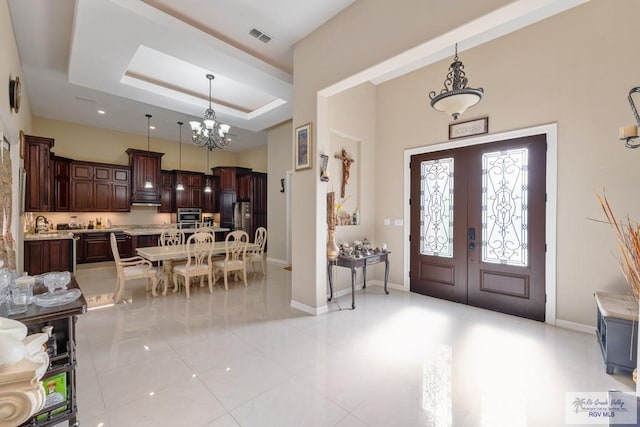 entryway featuring an inviting chandelier, french doors, baseboards, a raised ceiling, and visible vents