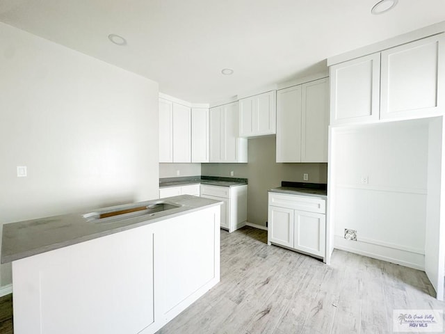 kitchen with light hardwood / wood-style flooring, white cabinets, and a kitchen island