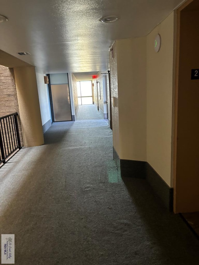 hallway featuring carpet flooring and a textured ceiling