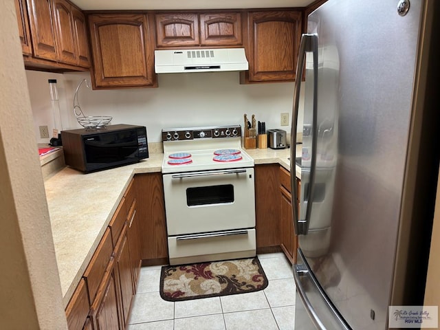 kitchen featuring light tile patterned floors, electric stove, stainless steel refrigerator, and exhaust hood