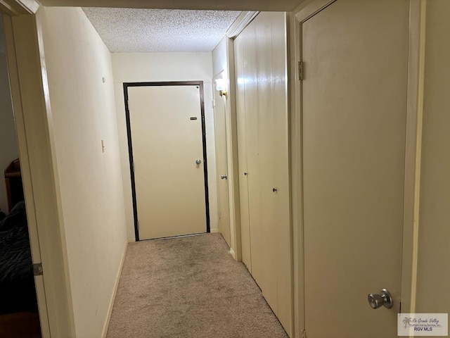 hallway featuring light carpet and a textured ceiling