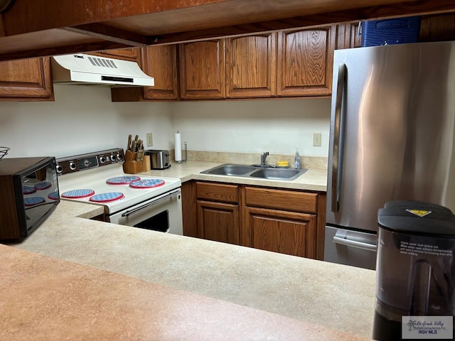 kitchen with range with electric stovetop, stainless steel refrigerator, and sink