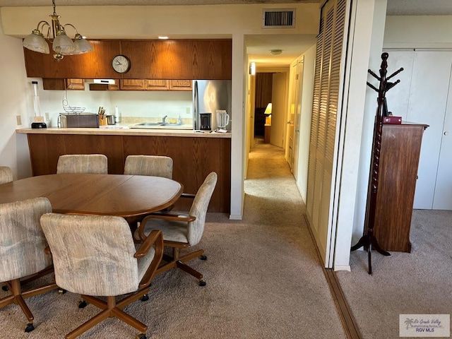 dining room featuring a notable chandelier, sink, and light carpet