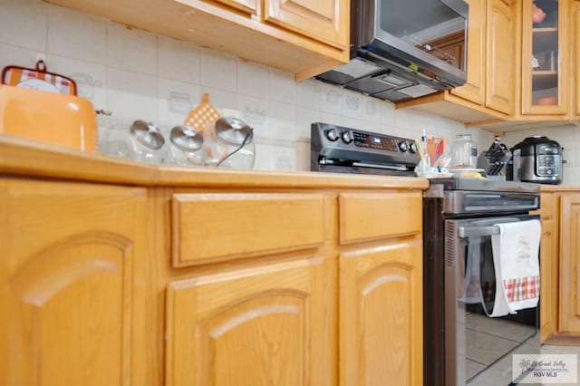 kitchen featuring decorative backsplash, light brown cabinetry, stainless steel appliances, and tile patterned floors