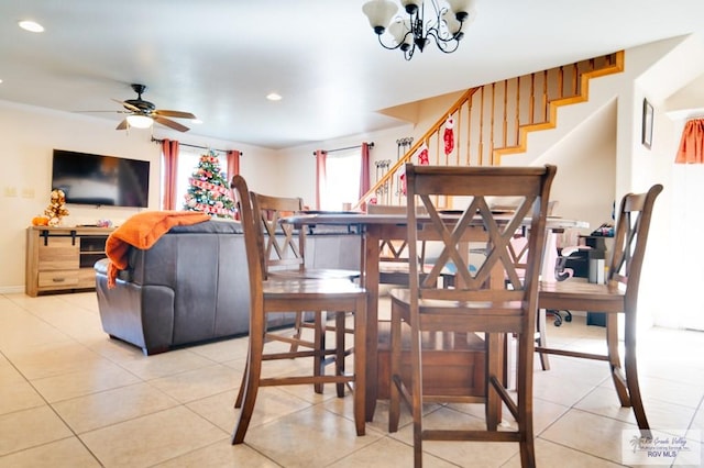 tiled dining room with ceiling fan with notable chandelier