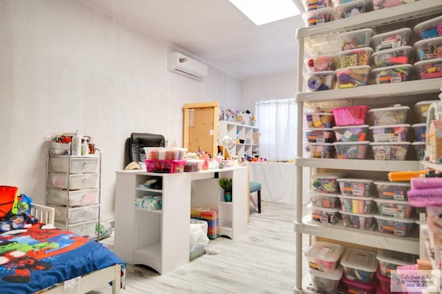 recreation room featuring a wall unit AC and light hardwood / wood-style floors